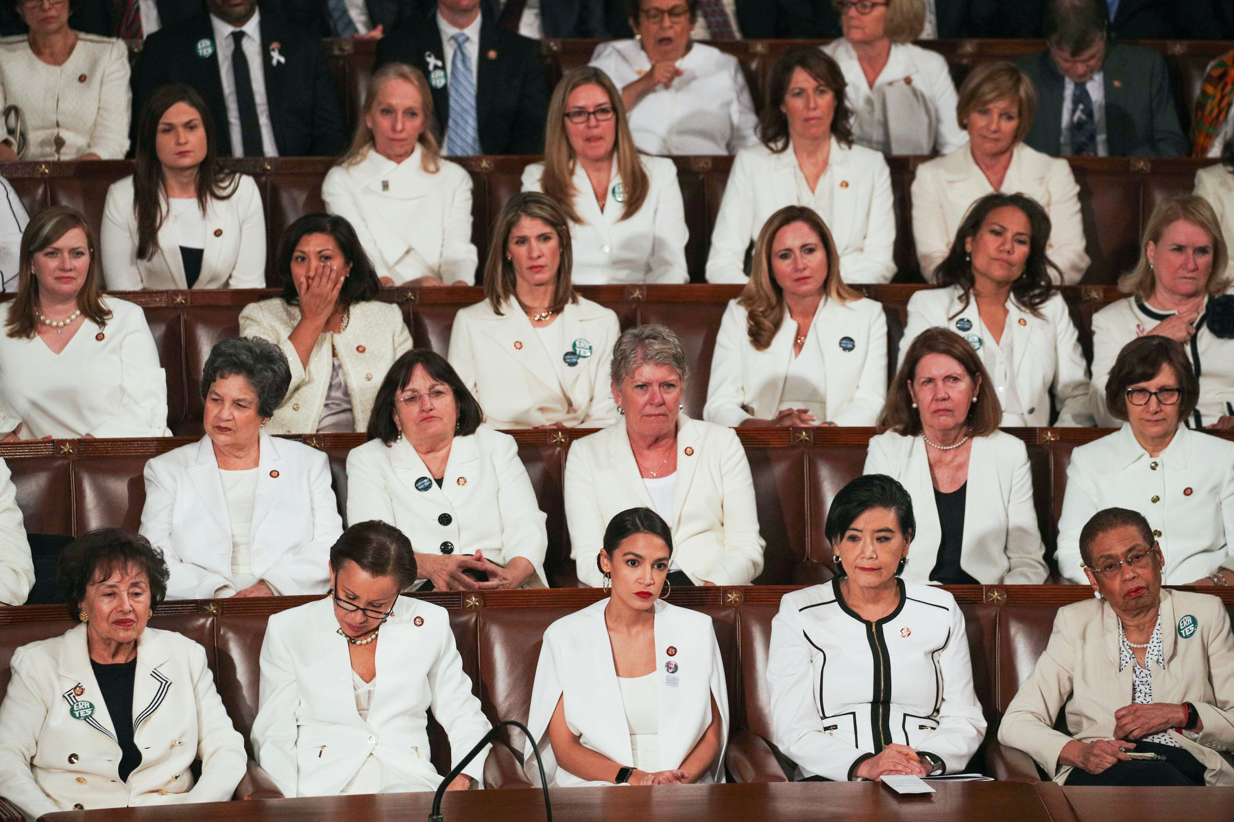 Four rows of women sit in Congress together, all wearing white.