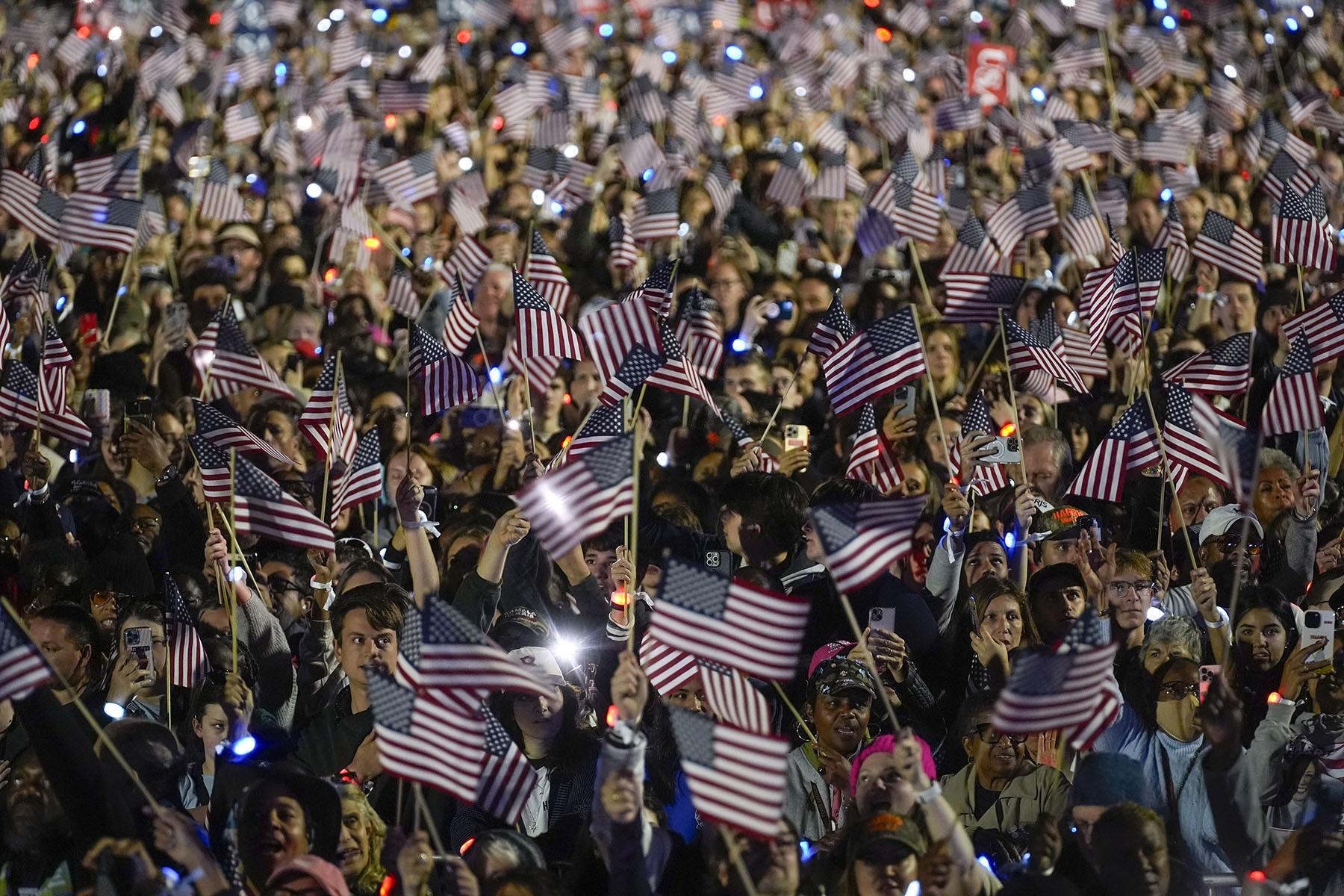 The crowd waves American flags as Vice President Kamala Harris speaks during a campaign rally on the Ellipse in Washington, D.C.