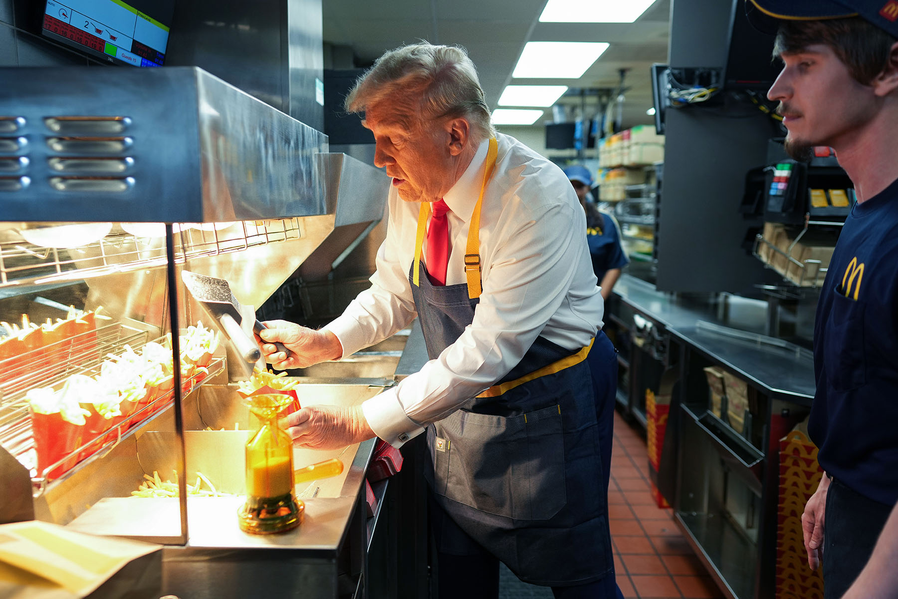 Former President Trump works behind the counter making french fries during a visit to a McDonald's restaurant.