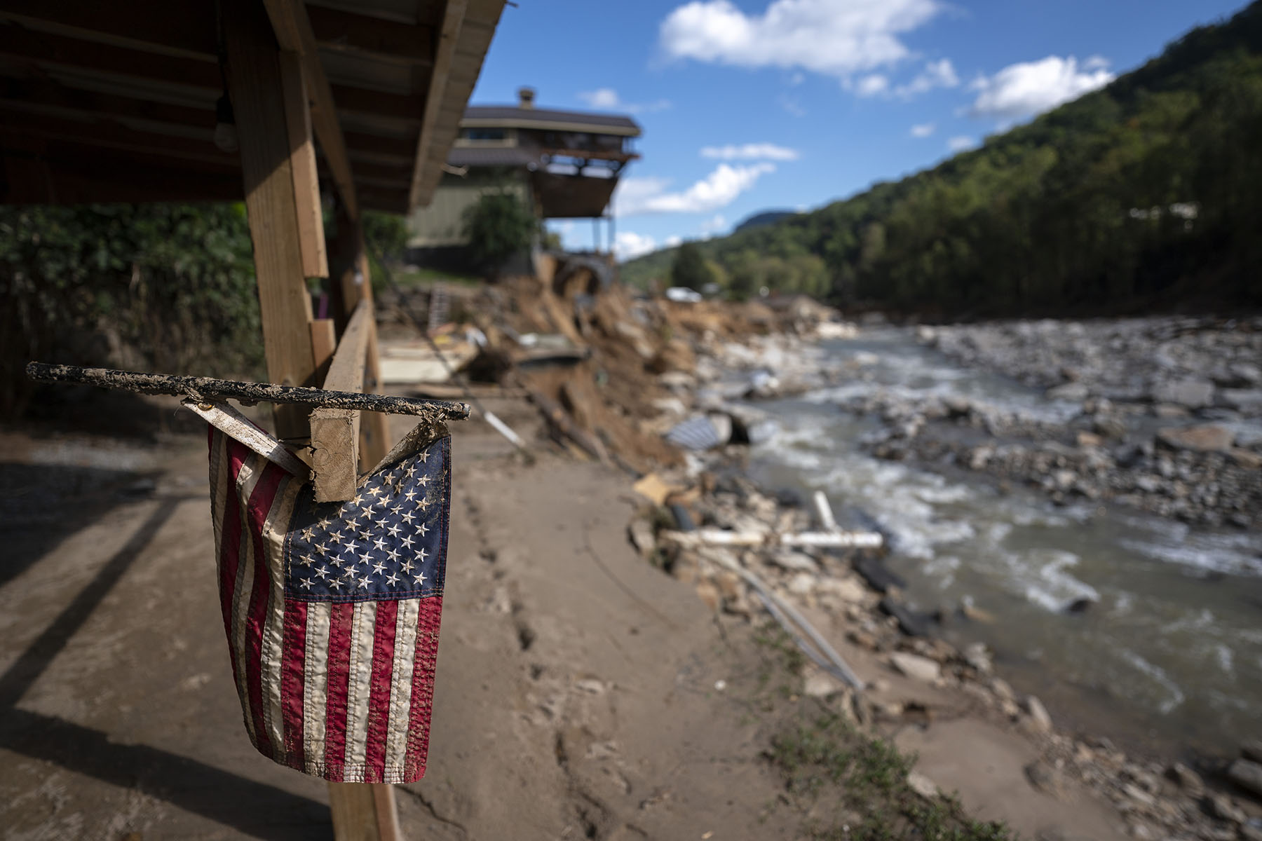 A tattered American flag is seen on a property amongst flood damage in the aftermath of Hurricane Helene in North Carolina