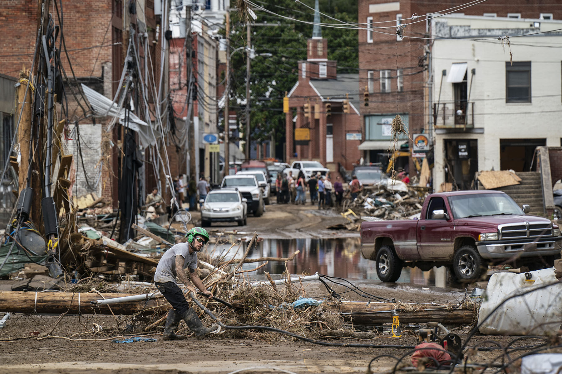 Workers, community members, and business owners clean up debris in the aftermath of Hurricane Helene in Marshall, North Carolina