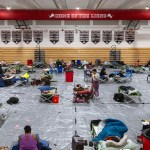 People are seen in an emergency shelter for Hurricane Helene inside a school gymnasium.