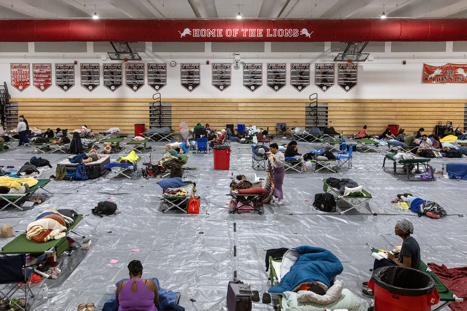 People are seen in an emergency shelter for Hurricane Helene inside a school gymnasium.