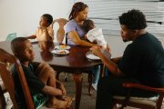 A mother and four of her sons sit at the dinner table, all facing and looking in different directions.