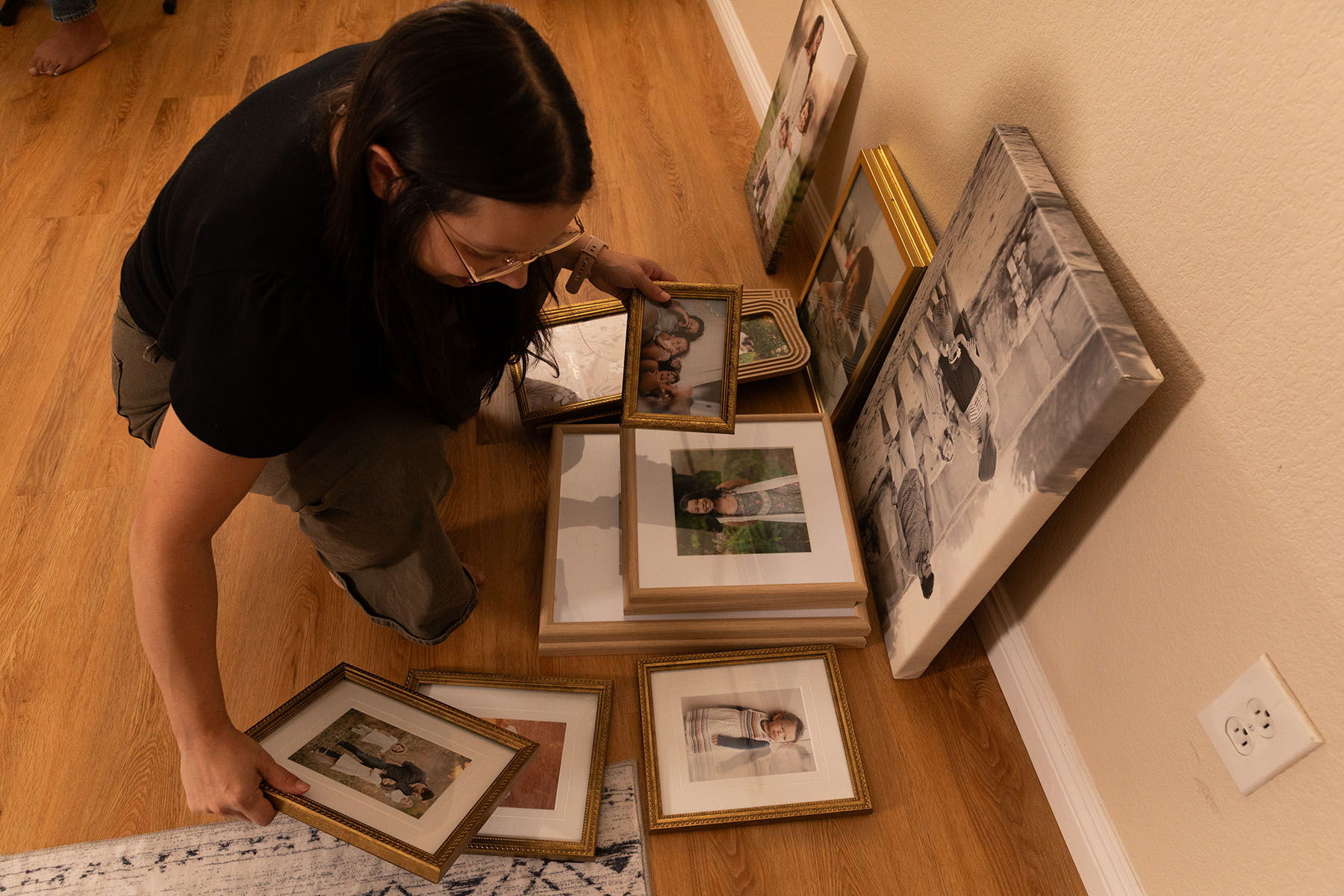 Jasmine Lopez organizing framed family photos on the floor of her home.