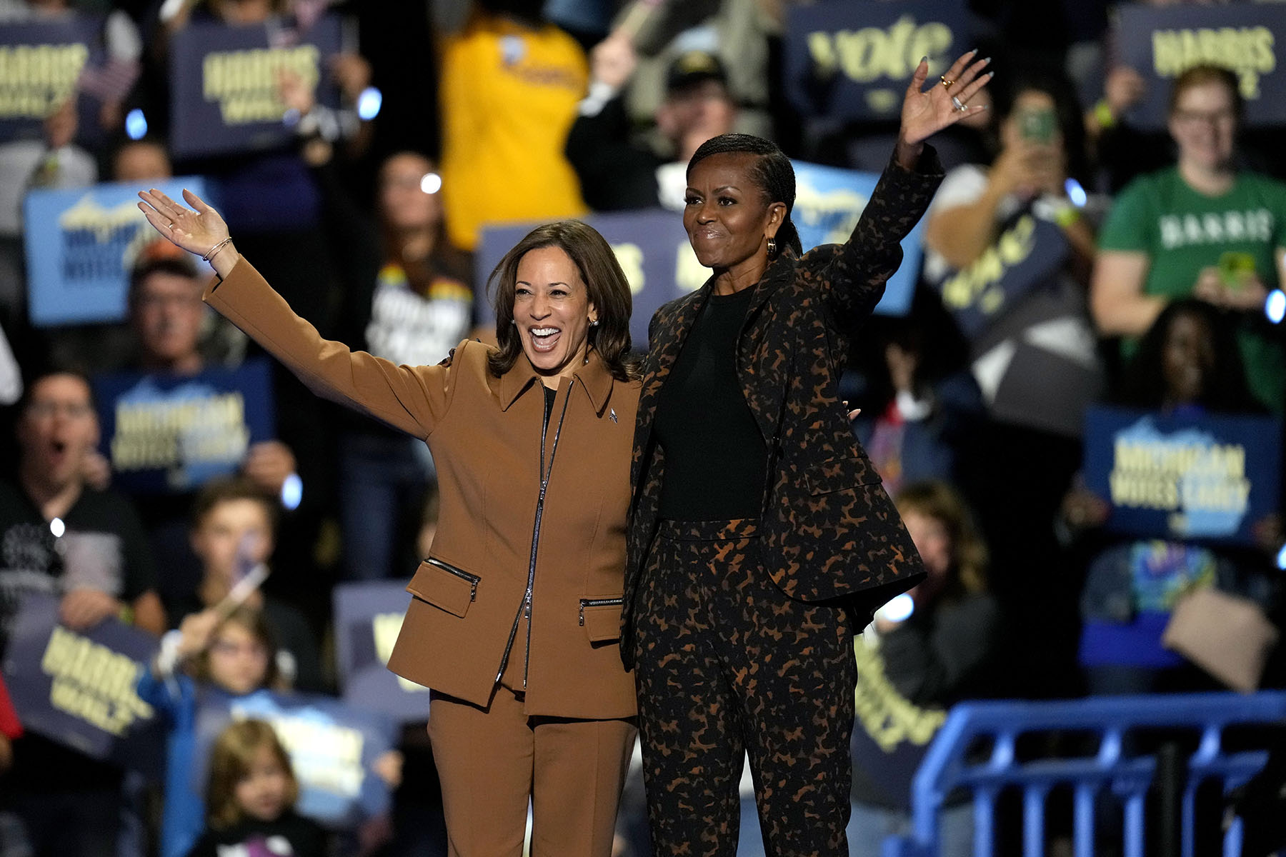 Vice President Harris and former first lady Michelle Obama wave to supporters from the stage at a campaign rally in Kalamazoo, Michigan.