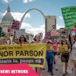 A group of protesters march in downtown St. Louis holding signs that say 