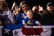 A woman holds a baby in a crowd.