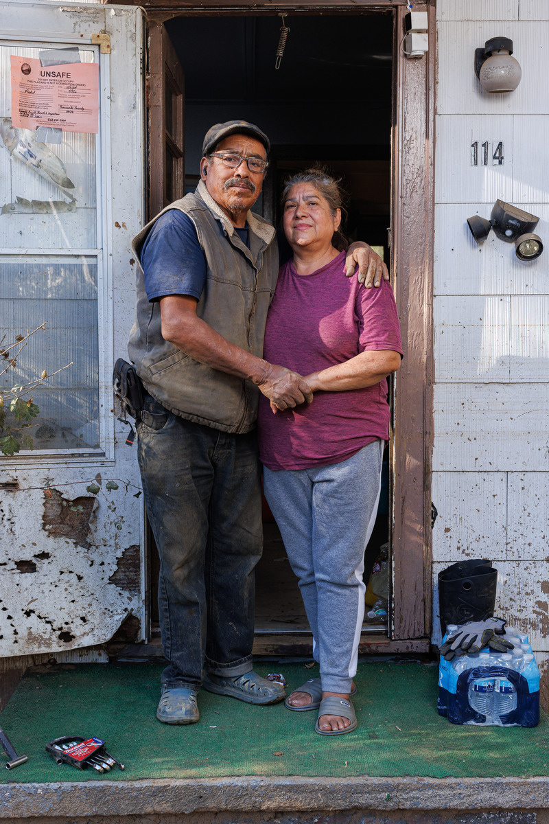 A man and woman stand in the doorway of a destroyed home.