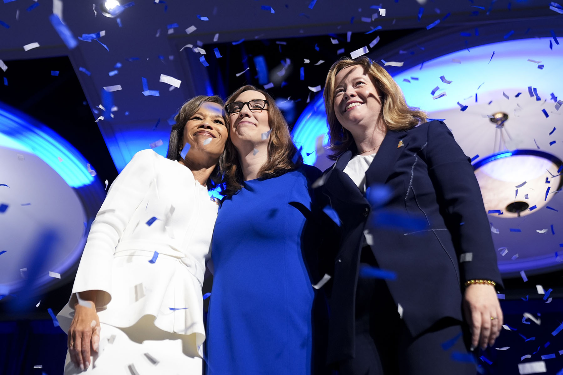 Rep. Lisa Blunt Rochester, Sarah McBride, and Lt. Gov. Elect Kyle Gay embrace on stage during an election night watch party.