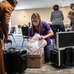 A group of people handle ballot tabulations.