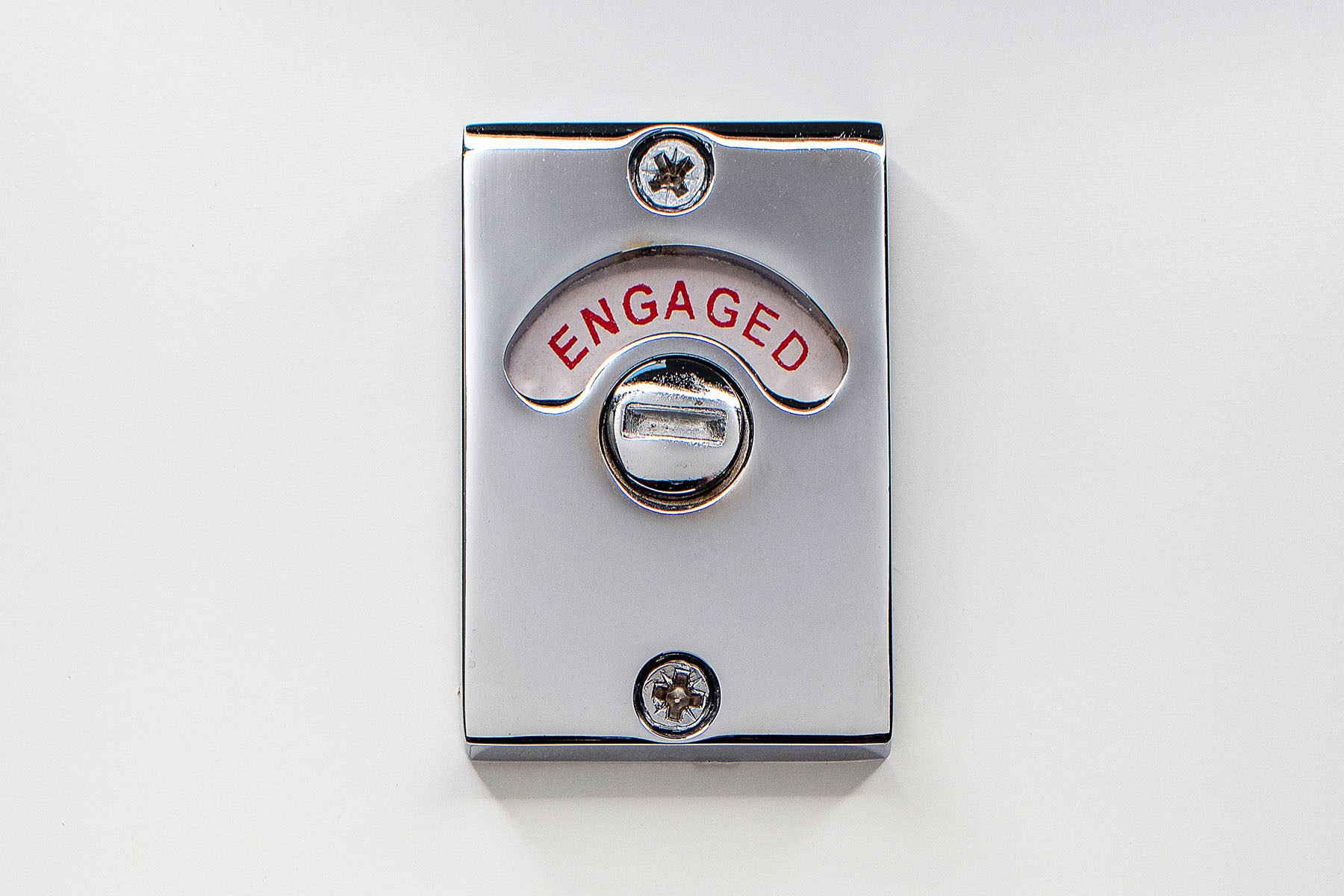 Close-up on bathroom toilet lock indicator in engaged (occupied) position.