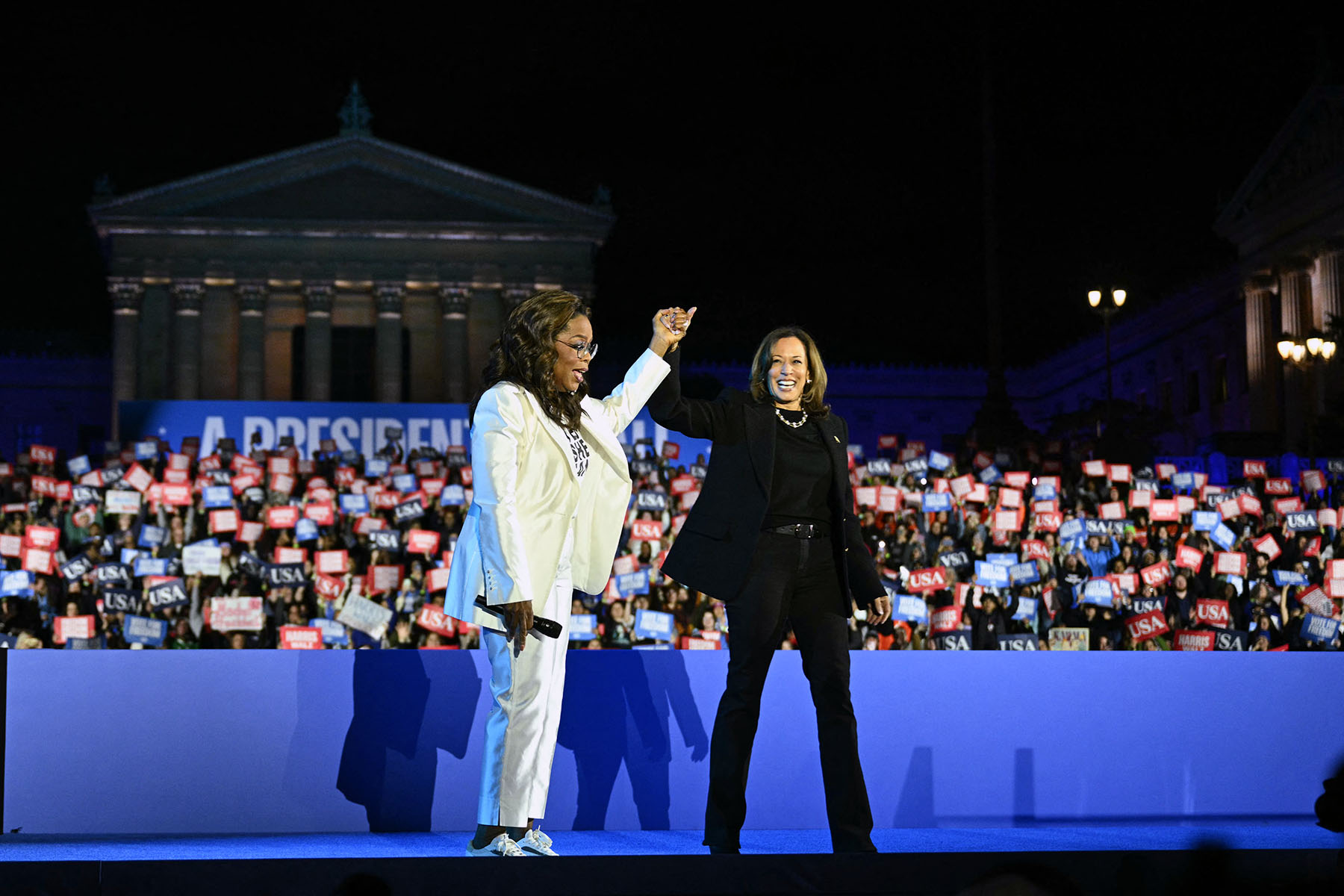 Oprah Winfrey holds up Vice President Kamala Harris' hand as she arrives onstage during a campaign rally on the Benjamin Franklin Parkway in Philadelphia, Pennsylvania.