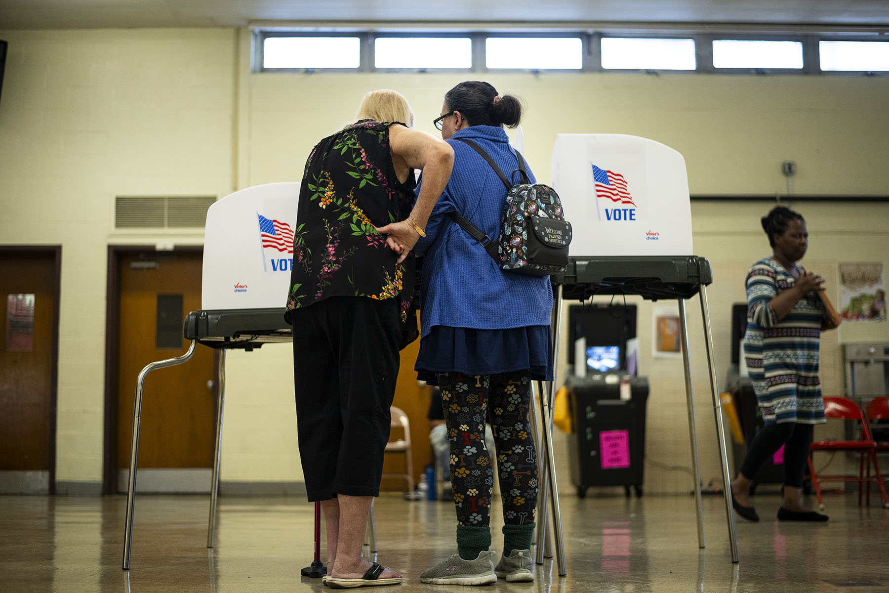 Two older women speak in front of voting booths at a polling location in Beltsville, Maryland.