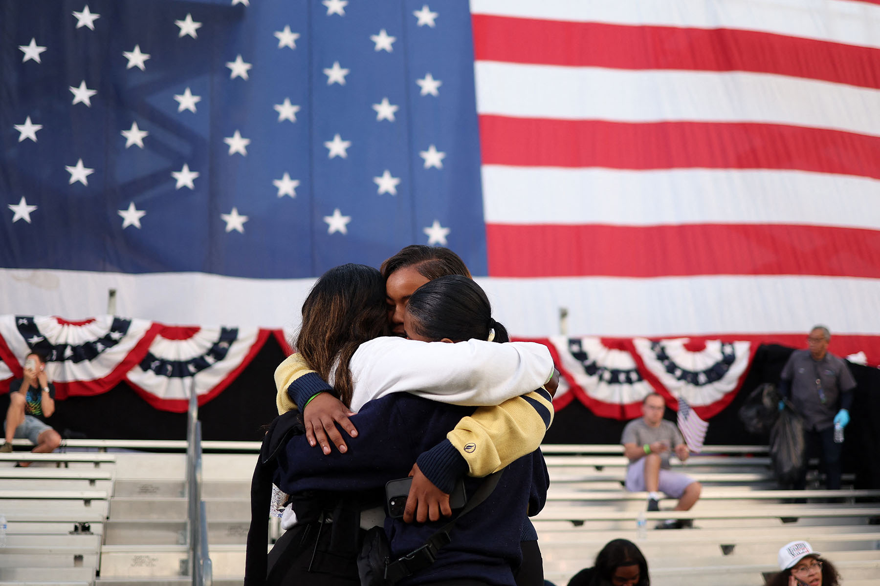 Three supporters in a group hug following Vice President Kamala Harris' speech at Howard University in Washington, D.C.