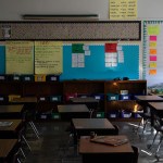 empty desks and cubbies are seen in a classroom.