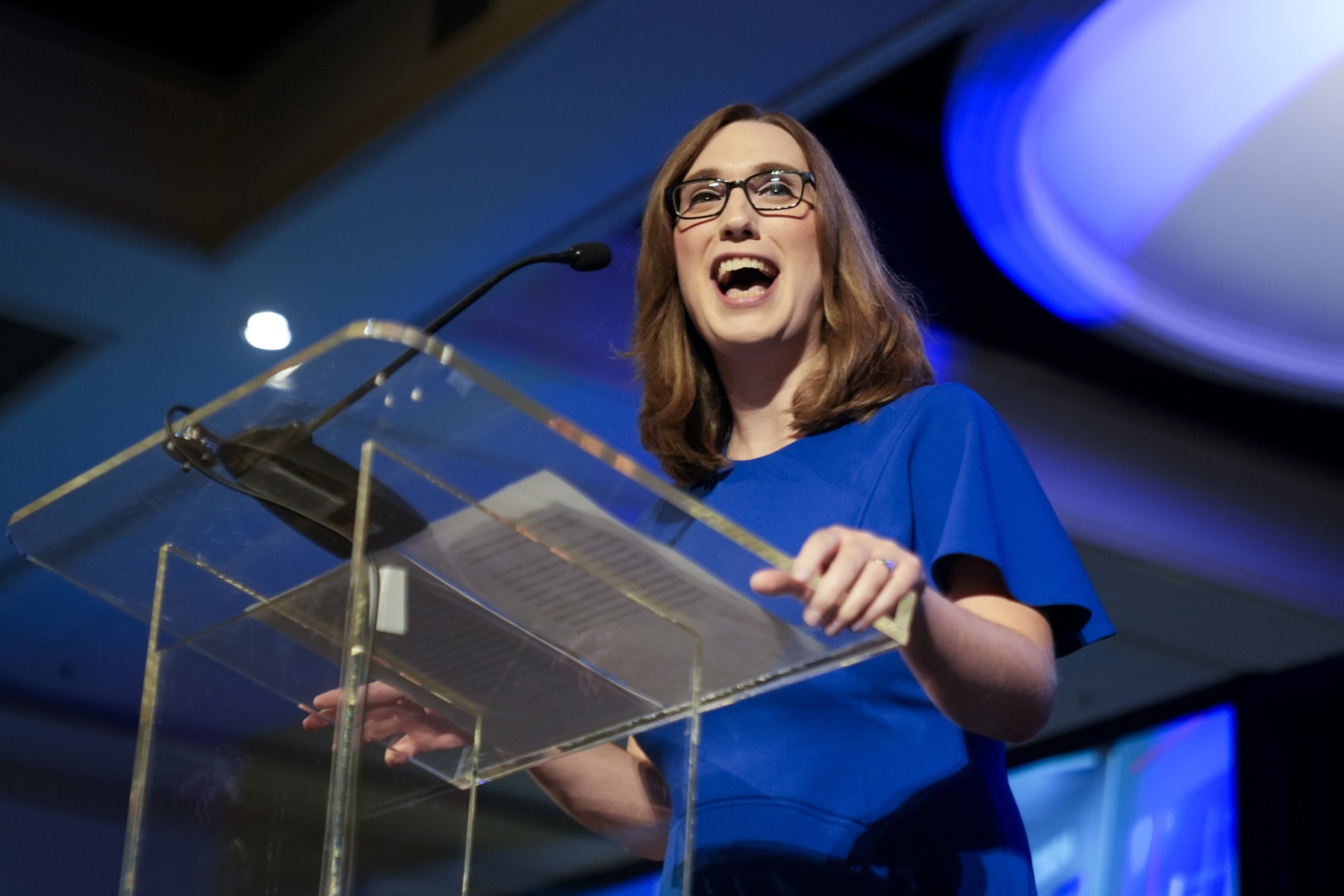 A woman smiles while standing at a podium.