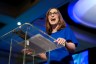 A woman smiles while standing at a podium.