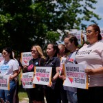 People hold signs during a news conference by Nevadans for Reproductive Freedom in Las Vegas.