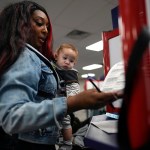 First-time voter Kayria Hildebran holds baby Kayden Hildebran as she fills out her ballot during in-person early voting.