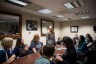 A group of parents and children from Little Lobbyists sit around a conference table during Rep. Jennifer Wexton’s first constituent meeting in 2019. Rep. Wexton stands at the table, smiling and engaging with attendees.