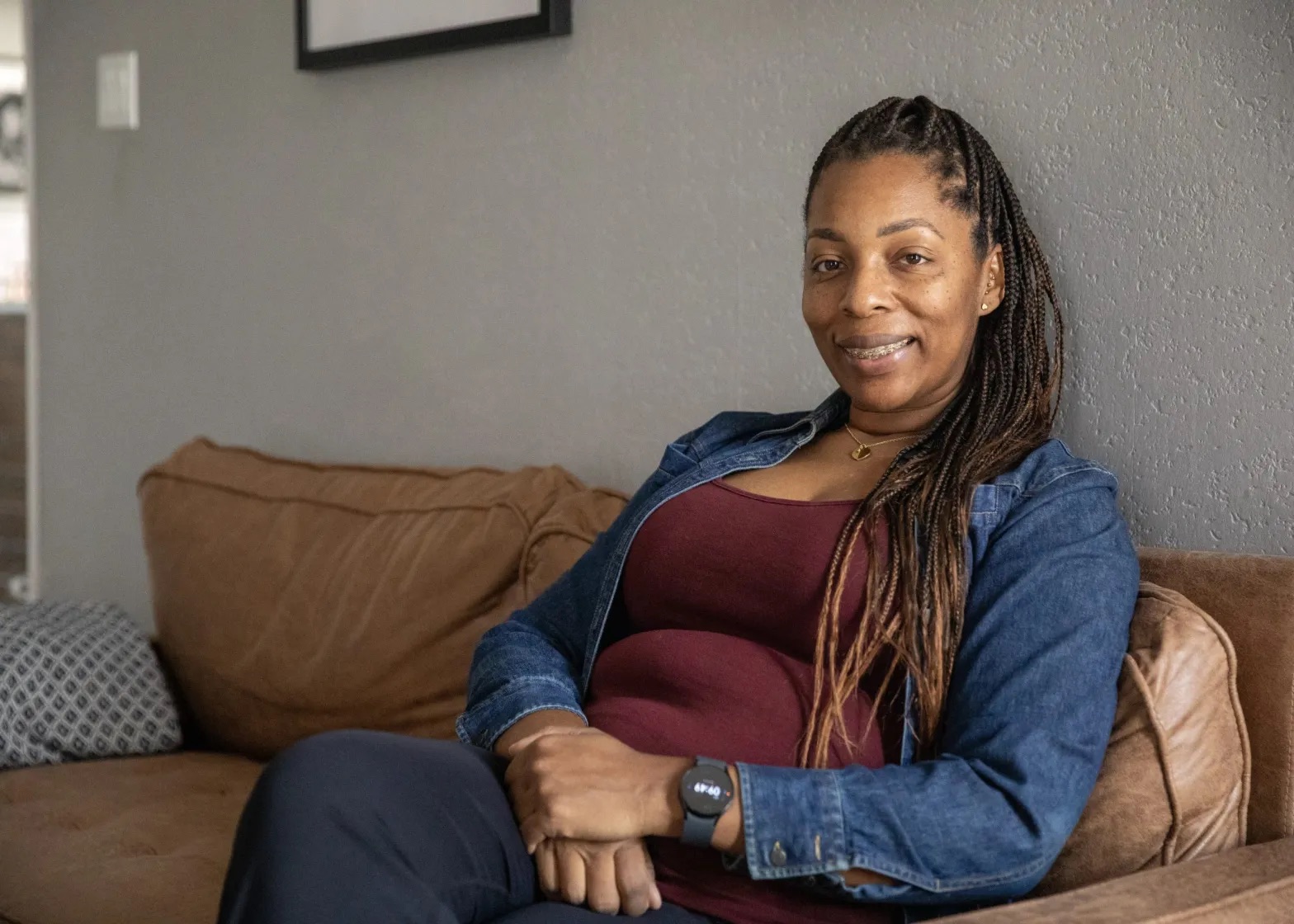 Portrait of Shanille Bowens smiling as she sits on a couch at Naturally Nurtured Birth Services.