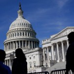 Silhouetted figures walk past the U.S. Congress building.