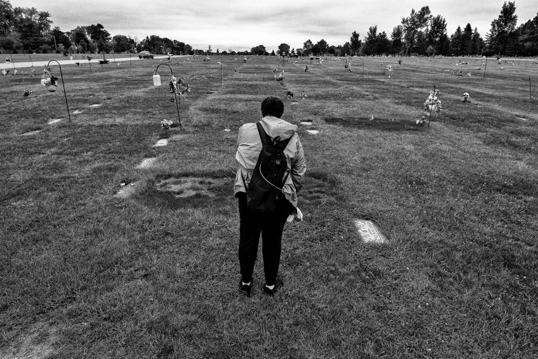 A woman stands facing a graveyard.