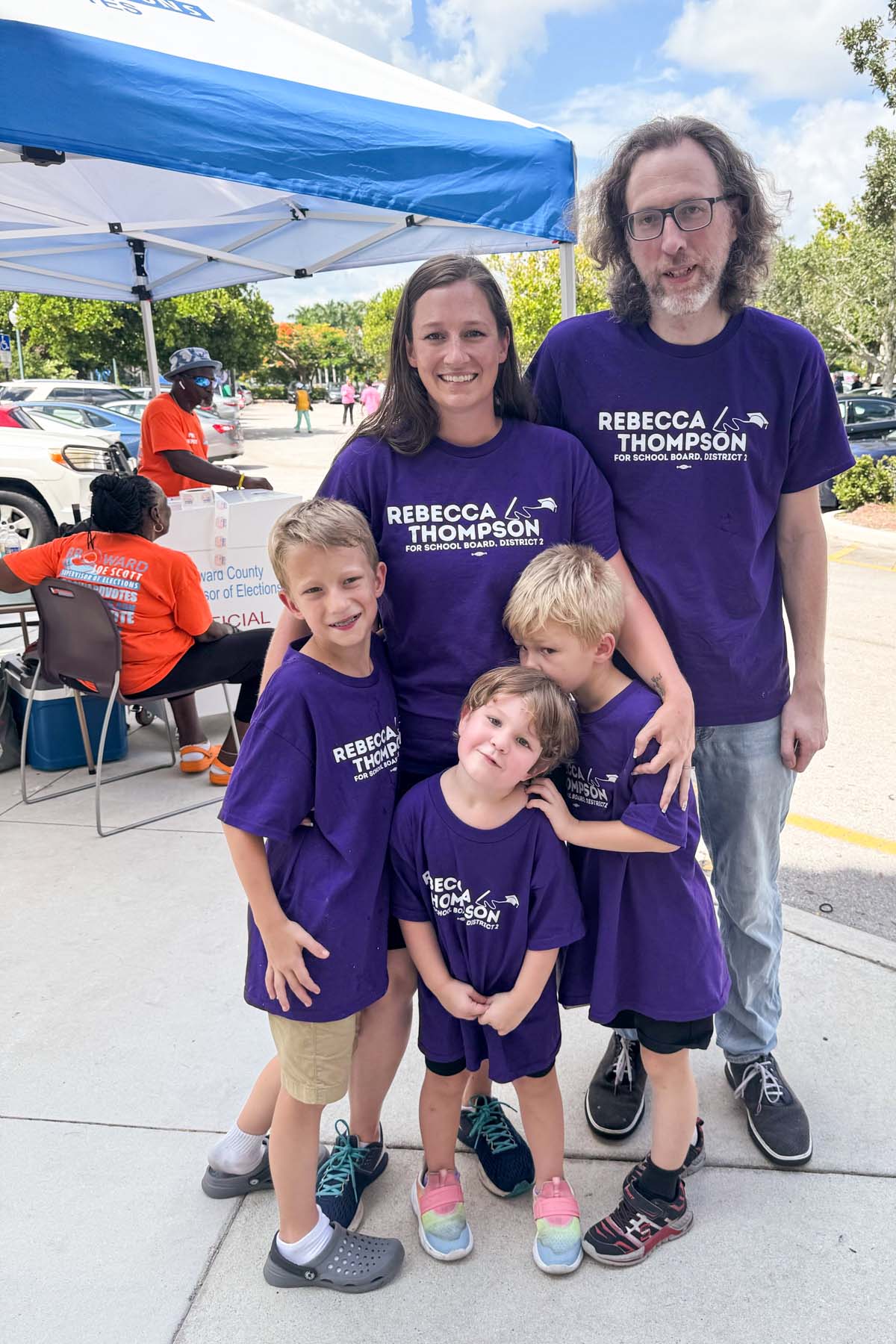 A family looks into camera, all wearing shirts saying "Rebecca Thompson".