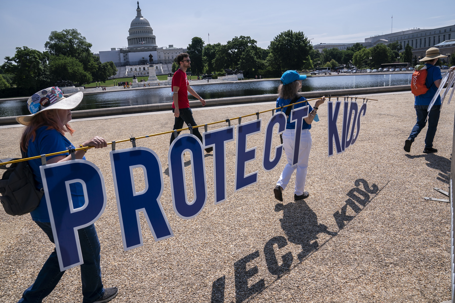 Rally attendees carry a sign past the U.S. Capitol that reads "Protect Kids".