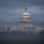 The U.S. Capitol building surrounded by fog and trees.