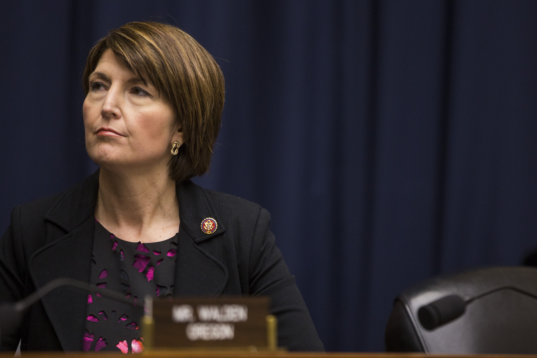 A woman sits in a chair alone, looking pensive.