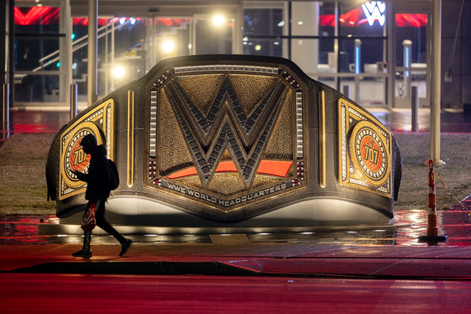 A person walks past a sculpture of a large WWE belt at WWE headquarters