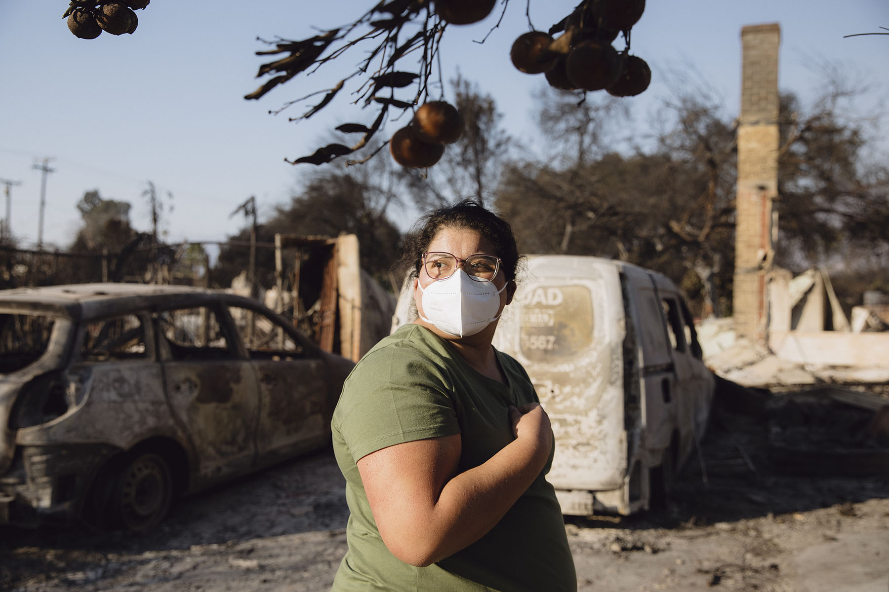 Sanchez wears a mask as she poses for a portrait in the rubble of her family home.