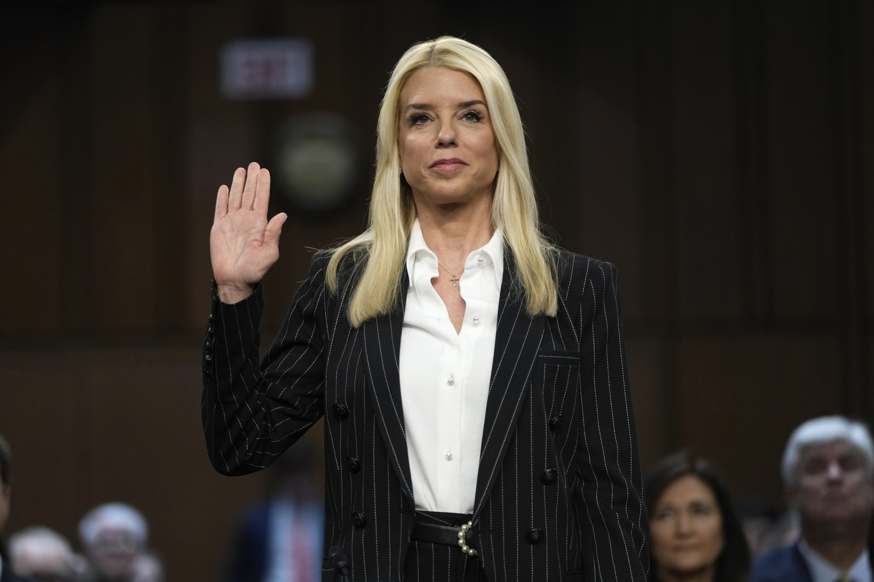 A standing woman raises her hand to be sworn in.