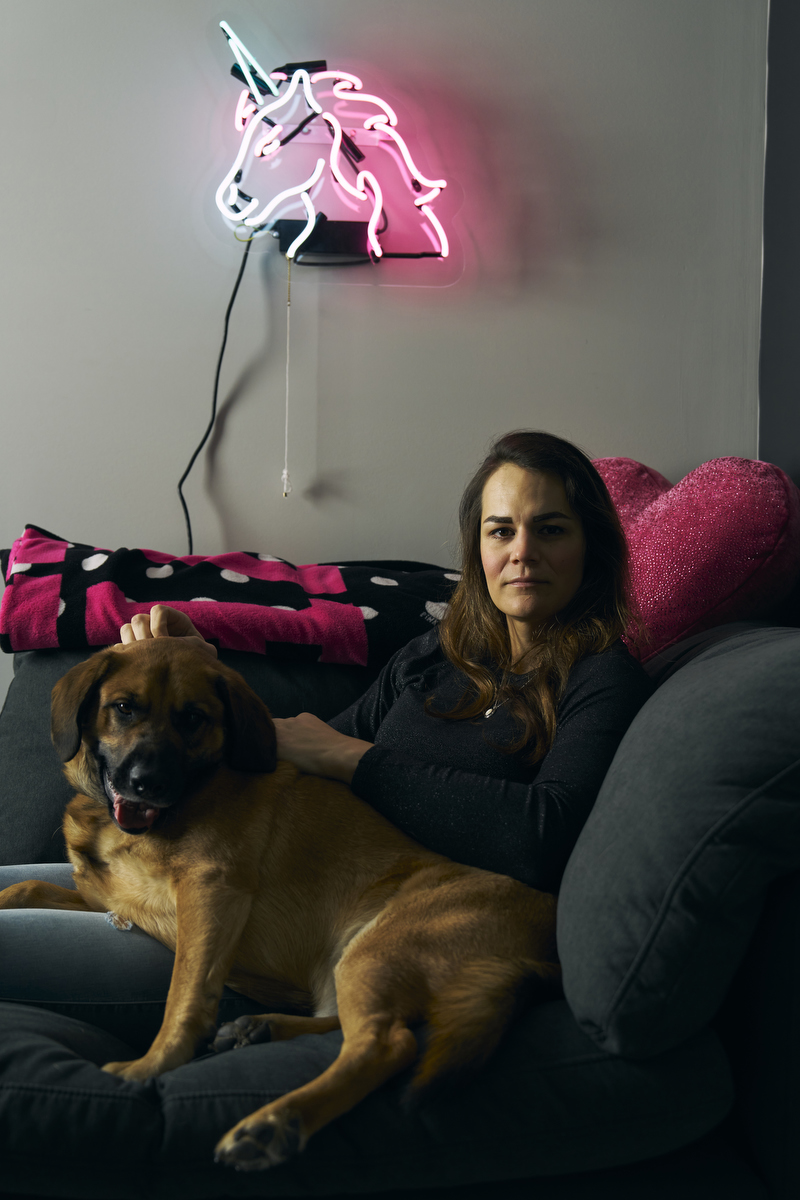 A woman sits on a couch with her dog.