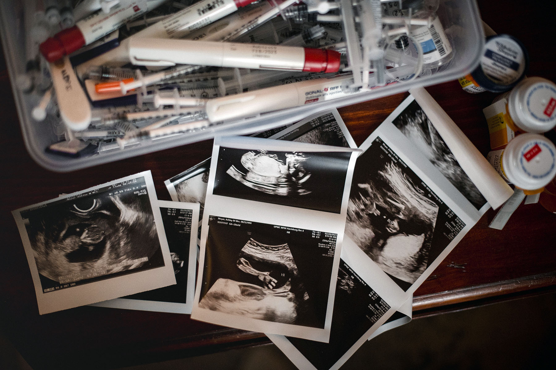 A container full of IVF needles, injections, syringes, old pill bottles and sonograms.