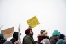 A line of protestors hold up signs saying 