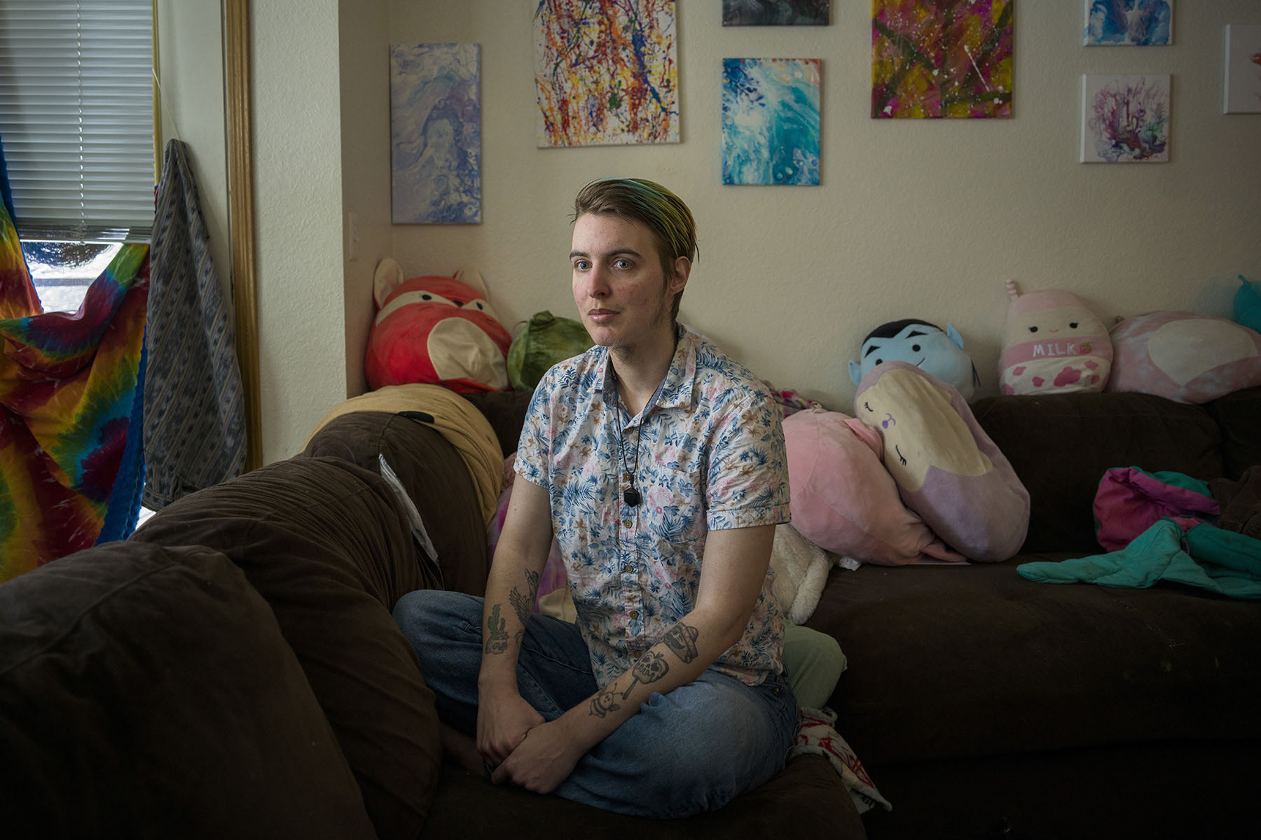 Ellis sits on a sofa surrounded by stuffed animals.