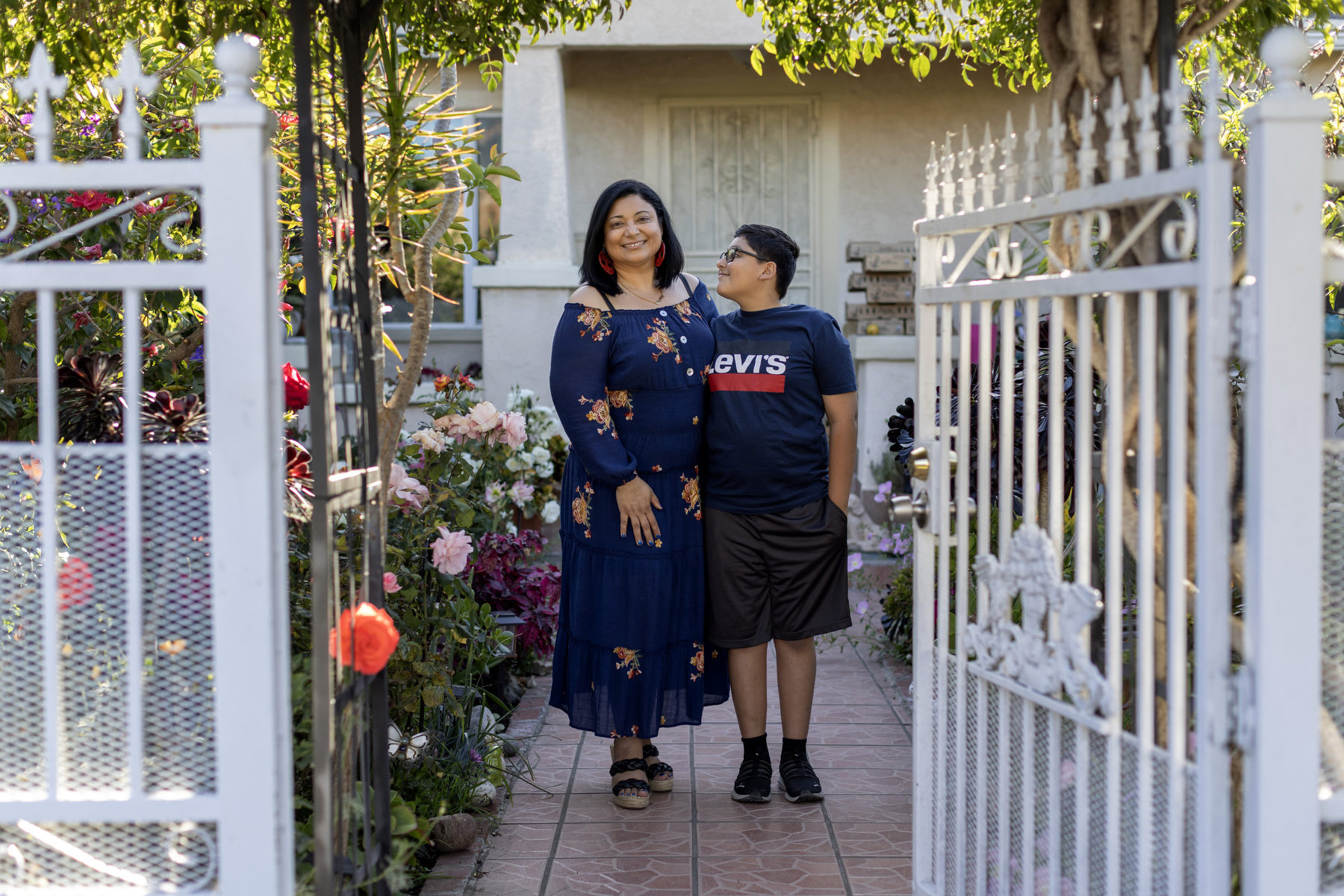 A woman smiles beside her son as he looks up at her.