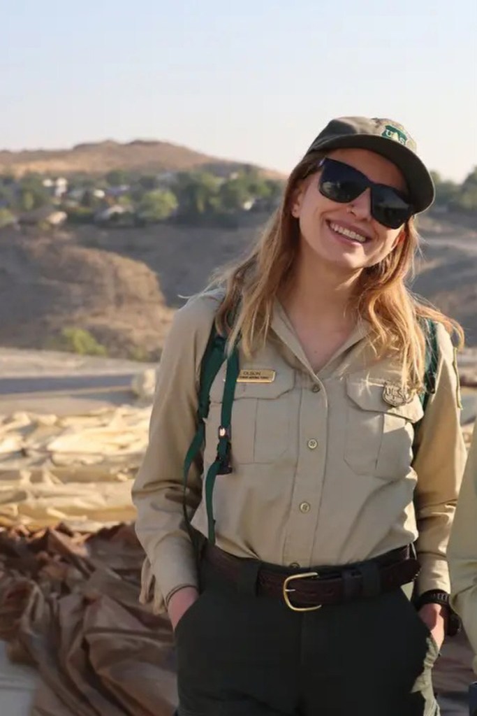 A woman in a ranger uniform smiles at the camera.