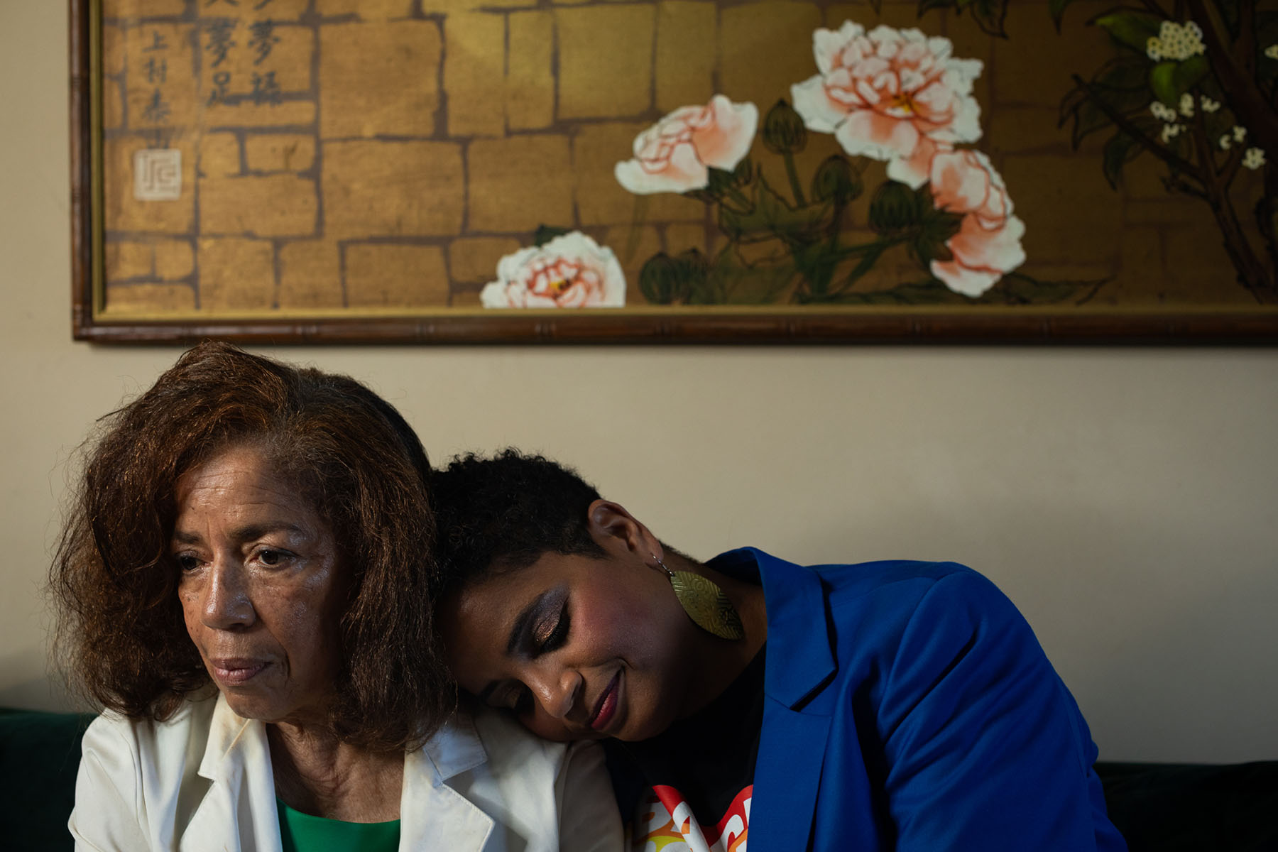Helen Jackson and her daughter Zakiya sit close together on a couch, Zakiya resting her head on her mother’s shoulder.
