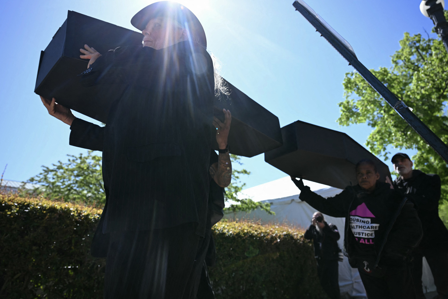 People carry mock black coffins down the street.