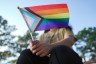 A person holds an LGTBQ pride flag which covers their face.