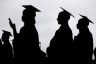 Graduates in graduation gowns shown in silhouette.