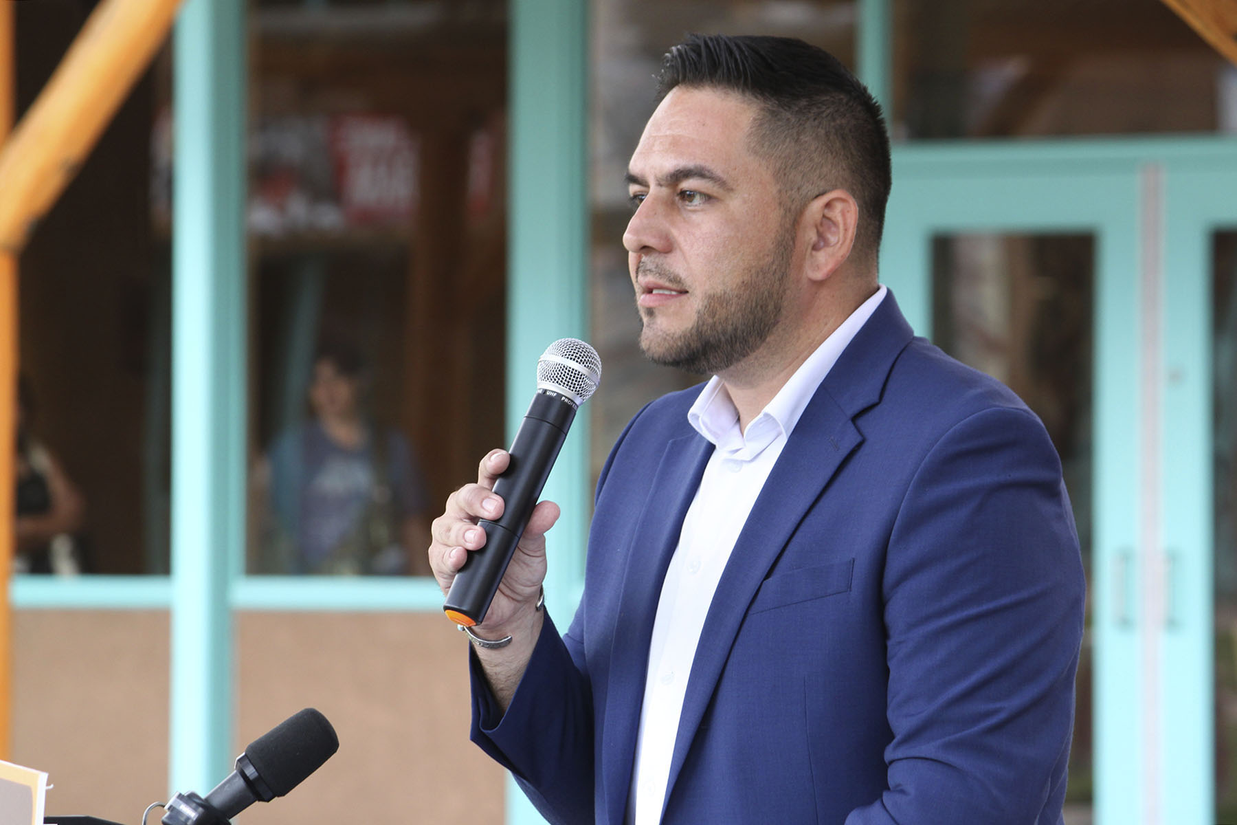 Gabe Vasquez speaks into a mic at a podium.