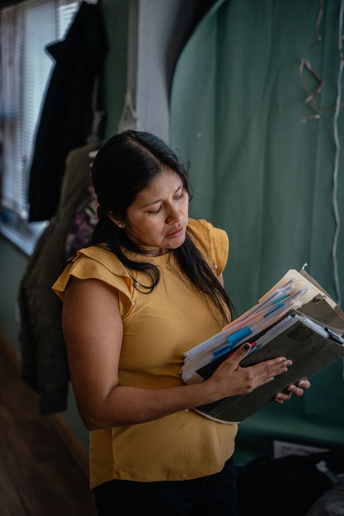 Ruano looks through stacks of folders of immigration documents at home.