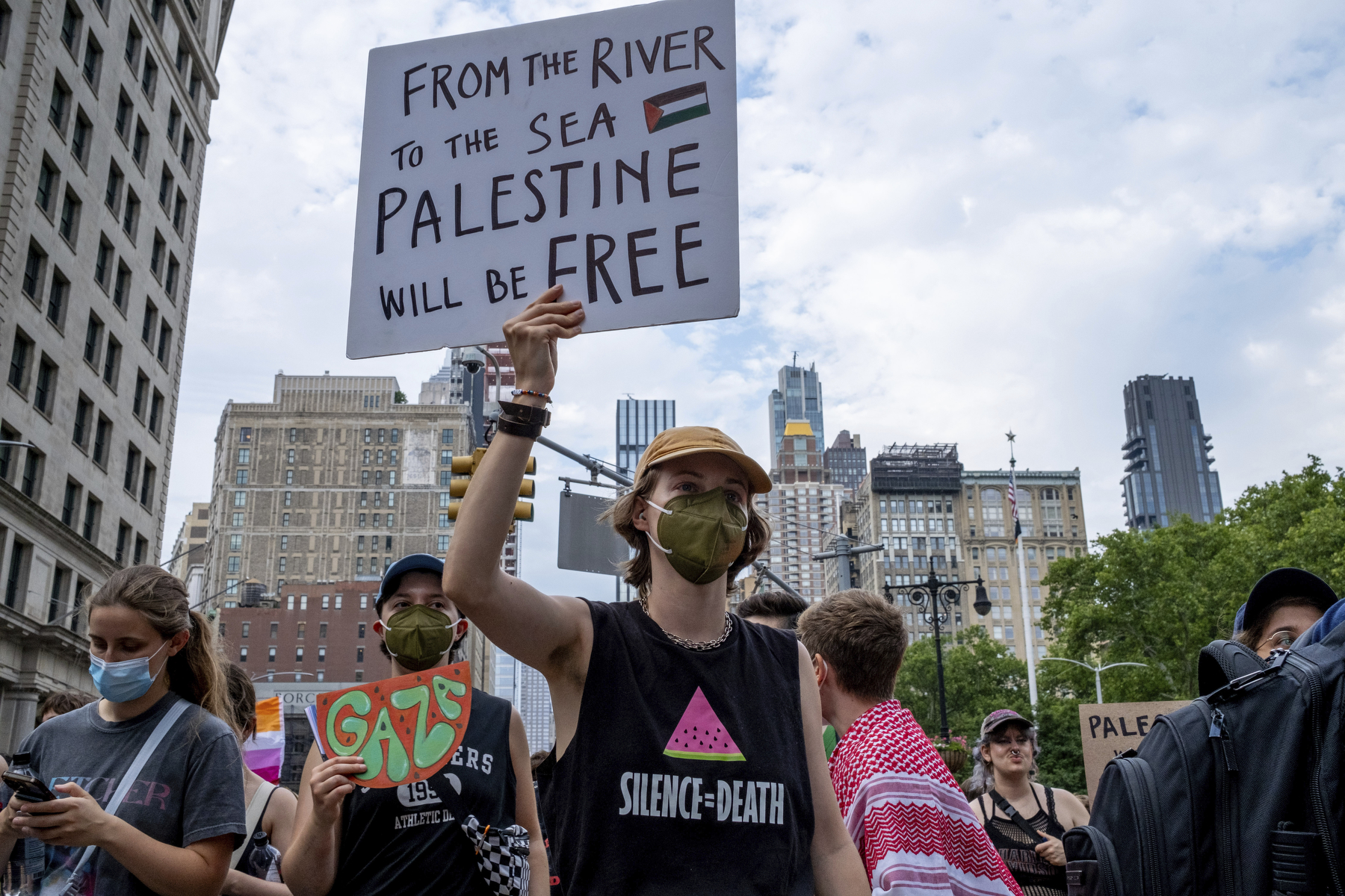 A person wearing a mask holds up a sign supporting Palestine during a march.