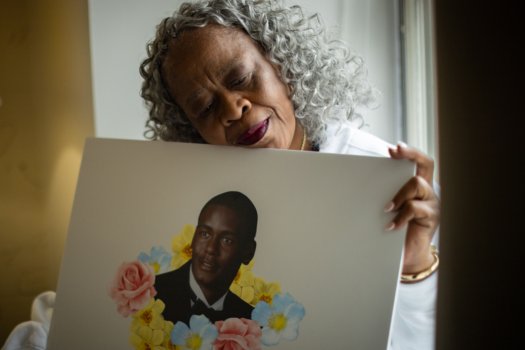 A woman lays her head on a poster depicting her late son.