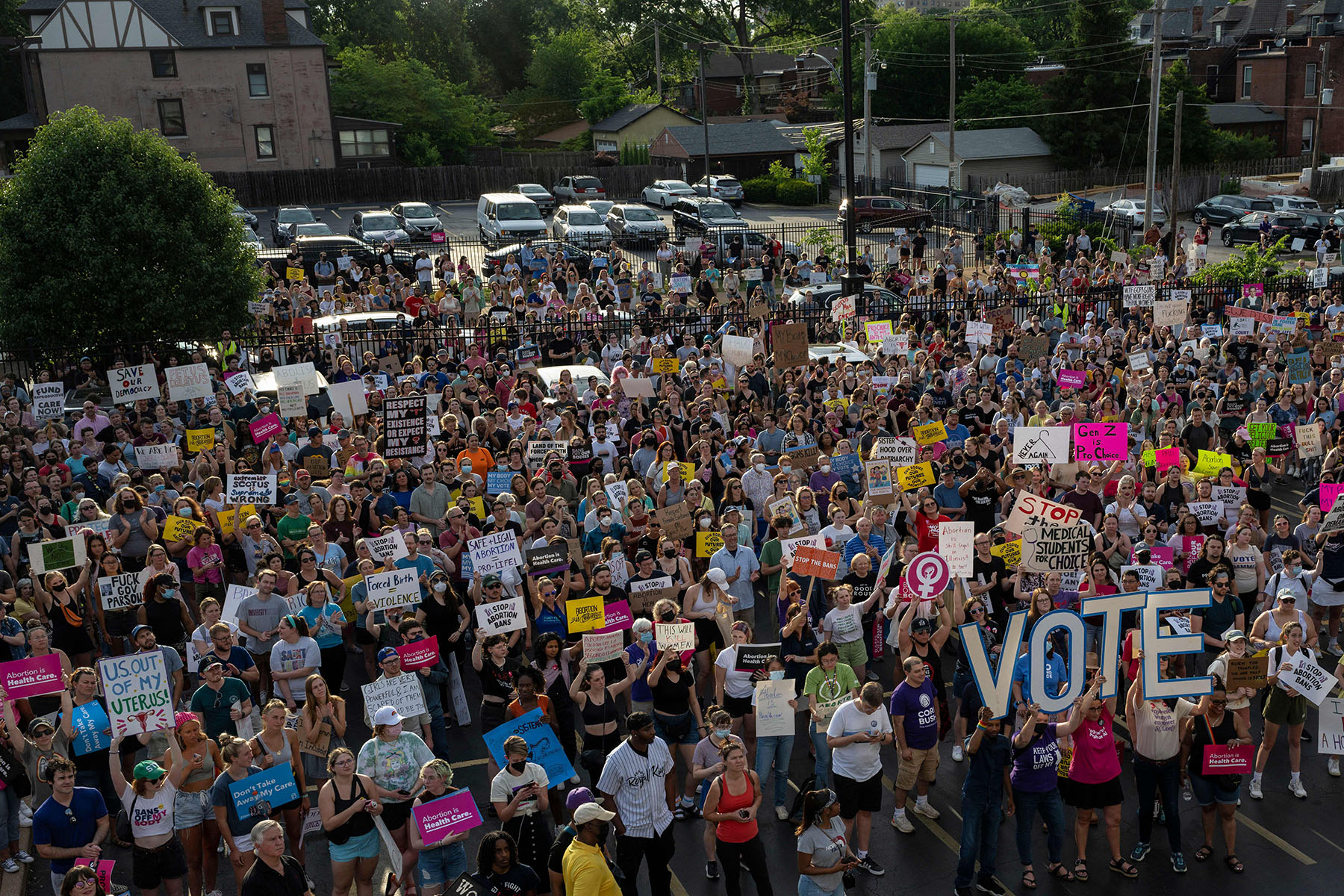 A large crowd holds signs supporting abortion access, including oversized letters spelling “VOTE,” during a protest in Missouri.